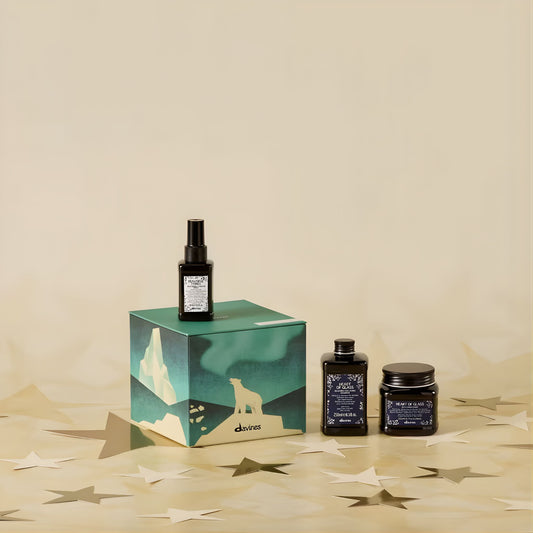 Three dark bottles with labels on a decorative box against a beige background